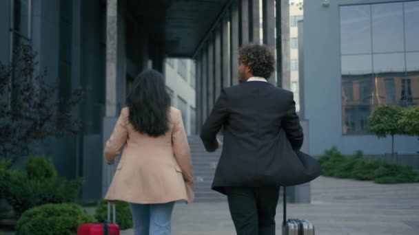 Dva obchodní spolupracovníci lidé Arabský businesswoman chůze město letiště terminál indický podnikatel s zavazadly zavazadla firemní výlet žena muž cestování chůze dát vysoké pět týmová práce gesto zpět pohled - Záběry, video