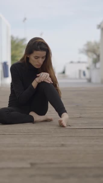 Mujer joven vestida de negro se sienta al aire libre mirando sorprendido, push-in - 1080 Vídeo vertical - Metraje, vídeo