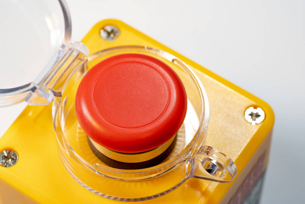 Vista detallada de un botón de parada de emergencia rojo interruptor de seguridad de la máquina industrial, botón de pánico rojo amarillo con tapa abierta levantada. Equipo pesado, seguridad en el lugar de trabajo, seguridad de los trabajadores - Foto, Imagen