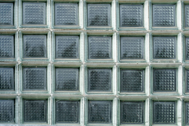 Γκρο πλαν άποψη ενός συμμετρικού και υφή τοίχο μπλοκ γυαλιού, παλιά δεκαετία του '90 σχεδιασμό κτιρίου, παχύ τετράγωνο γυαλί μοτίβο, κανείς, μπροστινή άποψη, υψηλής ανάλυσης υλικό υφή φόντου, μετωπική βολή - Φωτογραφία, εικόνα