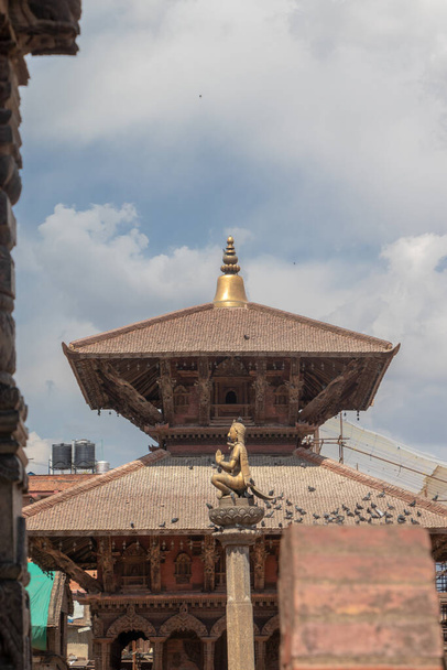 Patan Durbar Meydanı, Patan, Nepal 'deki namaste el hareketinde Garuda heykelinin yanındaki tapınaklardan birinin detaylarını oyuyor. - Fotoğraf, Görsel