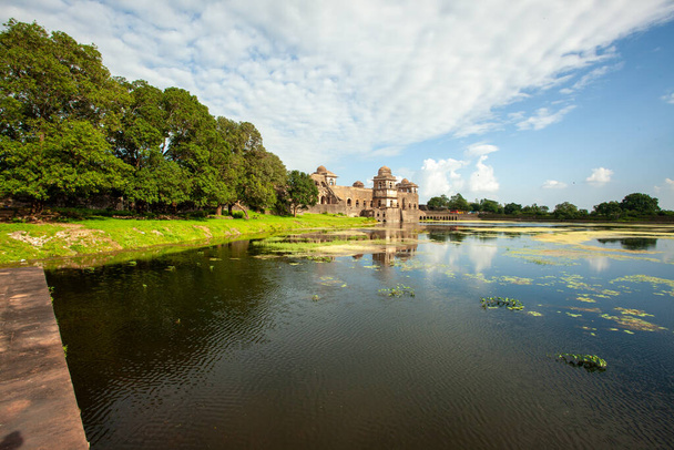 Majestic Jahaz Mahal at Mandu, monimutkainen arkkitehtuuri heijastuu rauhallinen vesistö, jota ympäröi vehreys ja kirkas taivas. - Valokuva, kuva