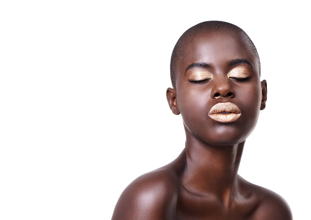Face of black woman, space or makeup with lipstick, cosmetics or beauty mockup in studio. Gold color, bald head or African girl model with glow, eyeshadow and skincare results on white background. - Photo, Image