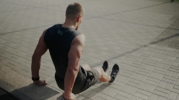 Un uomo in pantaloncini è sul pavimento in legno massello facendo flessioni con le mani a terra e gomiti piegando, cosce e piedi toccando il legno - Filmati, video