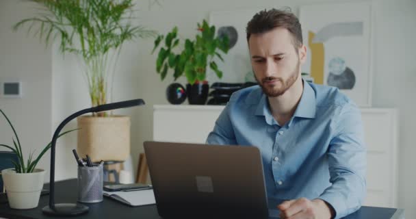Тривожний молодий бізнесмен закриває ноутбук, сидячи за столом у корпоративному офісі - Кадри, відео