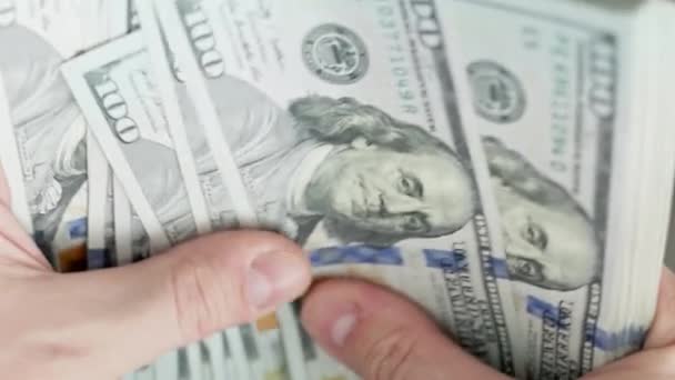 Кавказские руки, считая стопку банкнот по сотне долларов, крупным планом с избирательным фокусом и замедленным движением - Кадры, видео