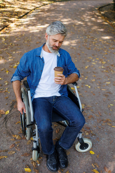 Утреннее спокойствие: инвалид расслабляется в парке с кофе - Фото, изображение