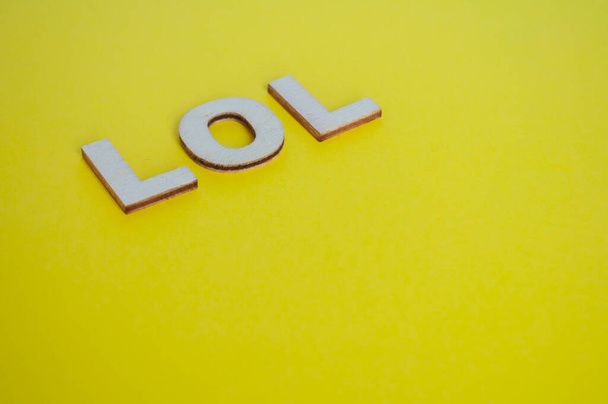 LOL ξύλινα γράμματα που αντιπροσωπεύουν γέλιο δυνατά σε κίτρινο φόντο. - Φωτογραφία, εικόνα