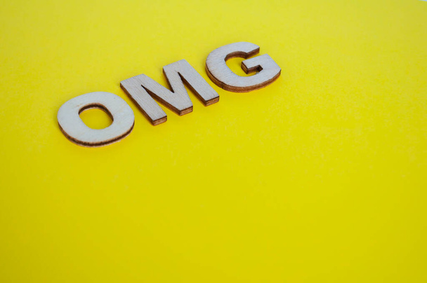 Drewniane litery OMG przedstawiające Oh My God na żółtym tle. - Zdjęcie, obraz