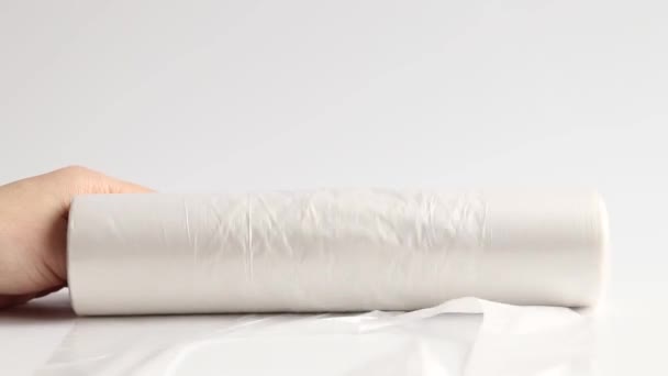 Nainen kädet rentoutuu rulla kertakäyttöisiä muovipusseja valkoisella pohjalla, kertakäyttöisiä pusseja - Materiaali, video