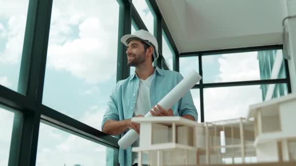 Gökdelen manzarasına bakarken yürüyen profesyonel mimar mühendisi. Masaya yerleştirilmiş ev modeliyle pencereye bakarken yetenekli proje yöneticisi proje planını tutuyor. Tasarım. İzleme - Video, Çekim