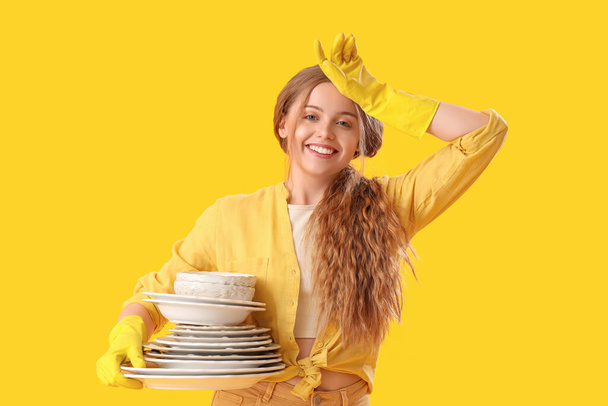 Nuori nainen, jolla on likaisia ruokia keltaisella taustalla - Valokuva, kuva