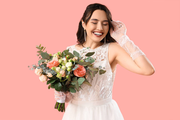 Hermosa novia con ramo de boda sobre fondo rosa - Foto, Imagen