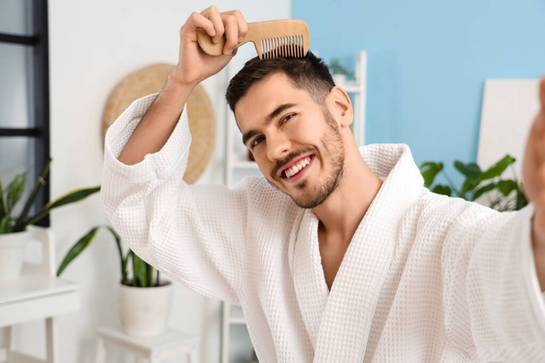 Jeune homme avec problème de perte de cheveux peignage dans la salle de bain, gros plan - Photo, image