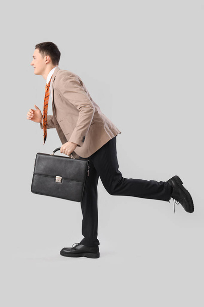 Divertido hombre de negocios con maletín funcionando sobre fondo ligero - Foto, imagen