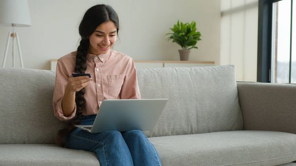 Nő ügyfél vásárlás online bankkártyával vásárolni áruk laptop biztonságos pénzügyi internetes fizetés e-kereskedelem üzlet boldog arab lány fizet digitális pénzt a honlapon megrendelés szállítás otthon - Fotó, kép