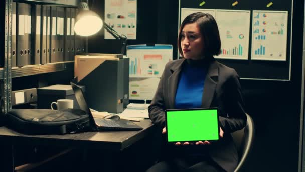 Private detective using tablet showing greenscreen template in incident room, working with witness statements and classified records. Agent holding device with isolated mockup. Camera A. - Footage, Video