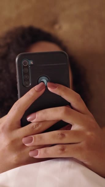 Smartphone wird von unkenntlich gemachter Frau in einem Bett getextet - FHD Vertikales Video - Filmmaterial, Video