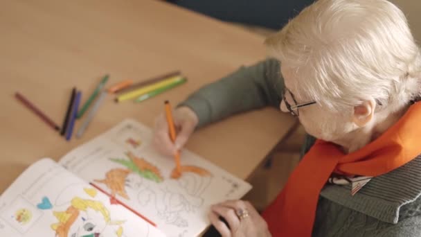 Αργή κίνηση βίντεο μιας ηλικιωμένης γυναίκας χρωματίζοντας μια κλήρωση σε ένα γηροκομείο - Πλάνα, βίντεο