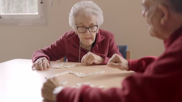 Slow motion video van ouderen spelen dominostenen geduldig in een verpleeghuis - Video