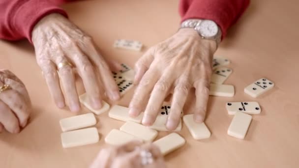 Vídeo de primer plano en cámara lenta de personas mayores clasificando las fichas de dominó en un geriátrico - Metraje, vídeo