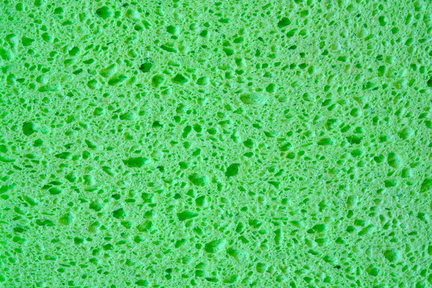 Grüner Schwamm mit Poren Textur Hintergrund für Grafiken. Makroaufnahme von Haushaltsschwammgewebe in Großaufnahme. - Foto, Bild