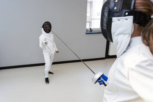 Children lunge on swords. A child in a class at a fencing school. High quality photo - Photo, Image