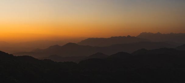 オレンジ色の空と日の出の背景を持つ山の層で旅行する自然 - 写真・画像