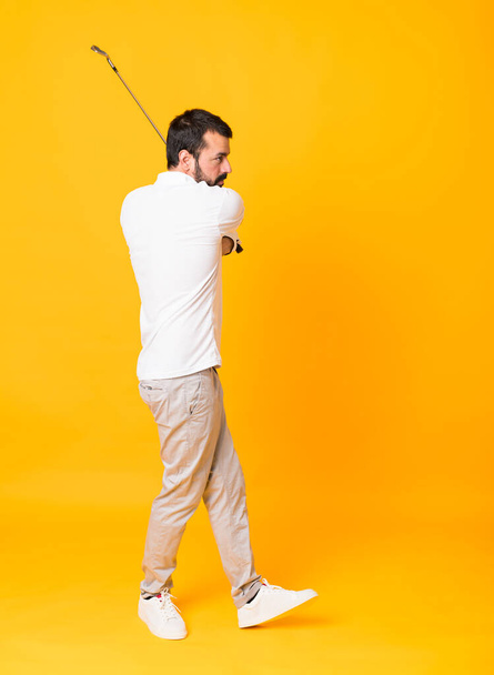 Tiro de comprimento total do homem sobre fundo amarelo isolado jogando golfe - Foto, Imagem