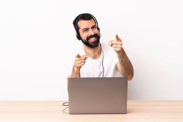 Telemarketer caucasian man working with a headset and with laptop pointing front with happy expression. - Photo, Image