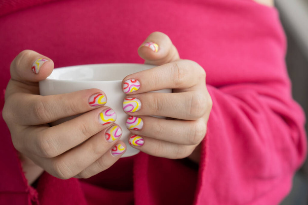 Stylish colorful summer female nails holding white cup of coffee or tea. Modern trendy stylish Beautiful manicure. Cute pastel nail minimalistic design concept of beauty treatment. Gel nails. Skin care. Beautician - Photo, Image