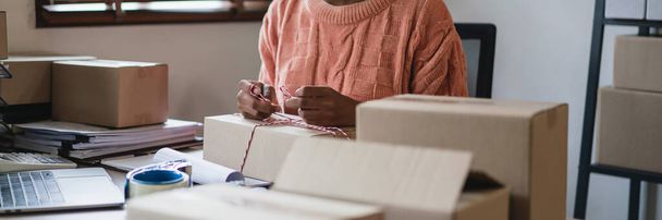 Африканські американські жінки використовують мотузку для зав'язування упаковки продукту і підготовки доставки клієнту. - Фото, зображення