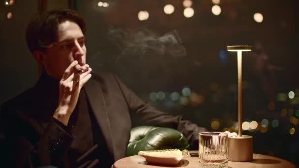 Ο νεαρός καπνίζει κομψά πούρο. Μέσα ενημέρωσης. Πανέμορφος άντρας καπνίζει πούρο στο εστιατόριο. Κινηματογραφικό κάπνισμα πούρου στο εστιατόριο.  - Πλάνα, βίντεο