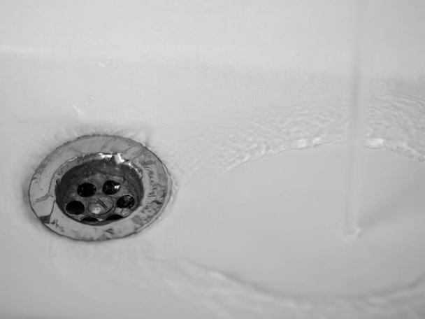L'acqua scorre in un lavandino in ceramica bianca - Foto, immagini