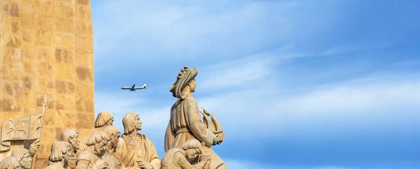 Monument aux découvertes en pierre calcaire, avec Henry le Navigateur tenant un navire regardant vers la mer avec un avion de passagers passant au-dessus de la tête pour atterrir à Lisbonne. - Photo, image