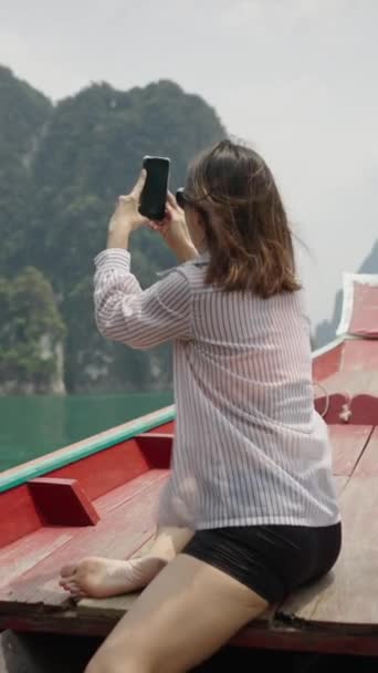 Σε μια ξύλινη βάρκα μια γυναίκα φωτογραφίζει τη λίμνη - Vertical 1080 Video - Πλάνα, βίντεο
