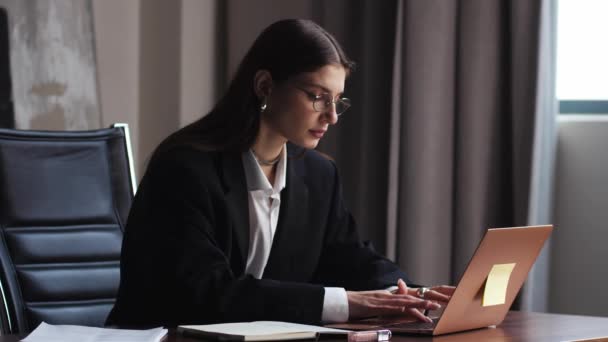 Mladá dospělá kavkazská obchodní žena profesionální marketingový manažer pomocí notebooku. Ženská podnikatelka pracující na počítačové správě digitálních dat sedí v práci ve velké moderní firemní kanceláři. Vysoká - Záběry, video