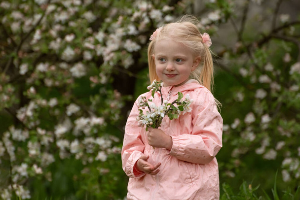 Bella ragazza caucasica con due code godere di primavera mela fioritura. Primavera. Ragazza in età prescolare in giardino fiorito - Foto, immagini