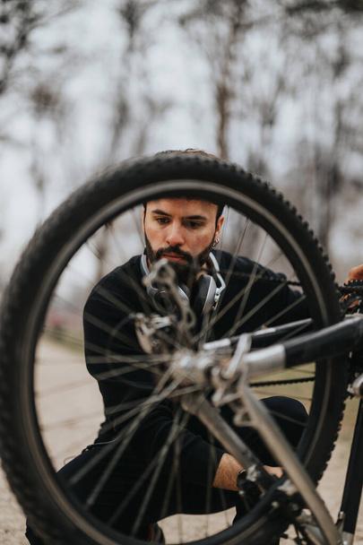 Εστιασμένος επιχειρηματίας σε περιστασιακή φθορά επισκευάζει το ποδήλατό του, απεικονίζοντας ένα μείγμα αναψυχής και μια προορατική, επίλυση προβλημάτων στάση. - Φωτογραφία, εικόνα