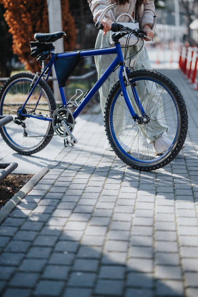 Un primer plano de una persona irreconocible con una bicicleta en una calle pavimentada, preparándose para un paseo urbano. - Foto, Imagen