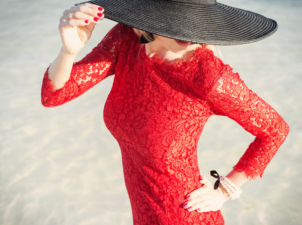 Stijlvolle vrouw dragen rode jurk en zwarte hoed - Foto, afbeelding