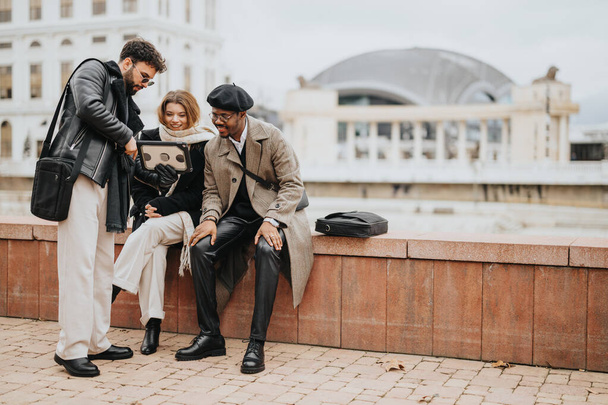Троє молодих підприємців, що займаються цифровим планшетом під час спільної зустрічі на вулиці в міському середовищі. - Фото, зображення