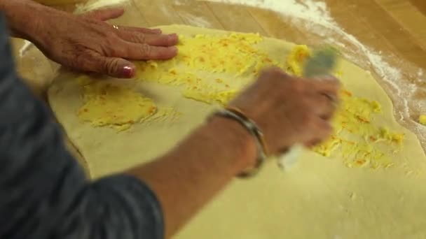 woman spreads topping on orange rolls - Filmati, video