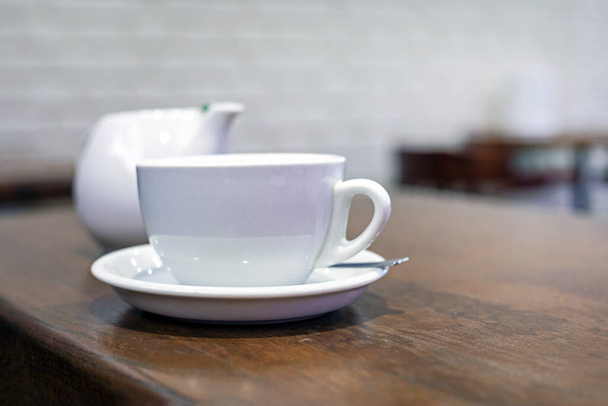 белая чашка и чайник на столе. Утренние закуски - Фото, изображение