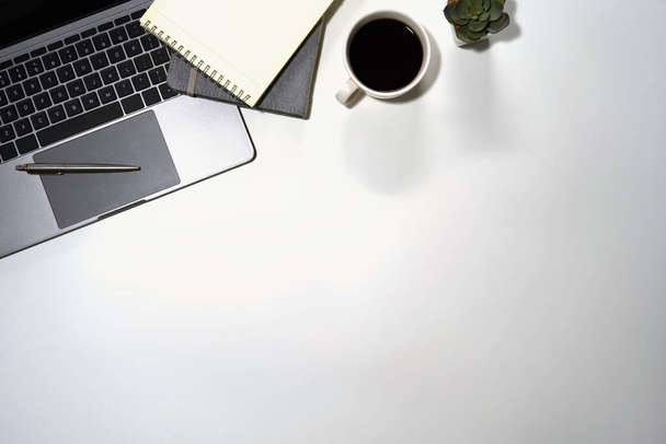 Escritorio de oficina blanco vista superior con laptop, bloc de notas, taza de café y plantas suculentas. - Foto, imagen