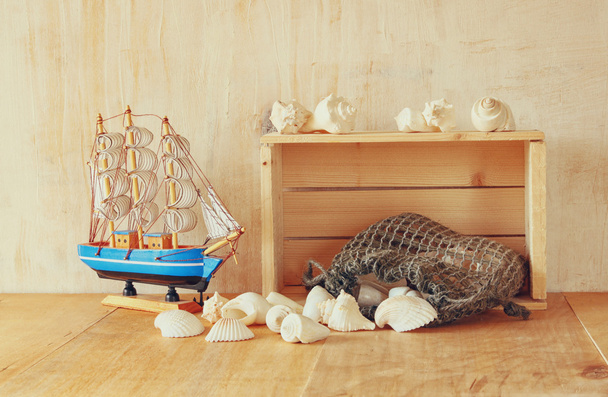 Vecchia cassa di legno, barca e conchiglie naturali sul tavolo di legno
 - Foto, immagini