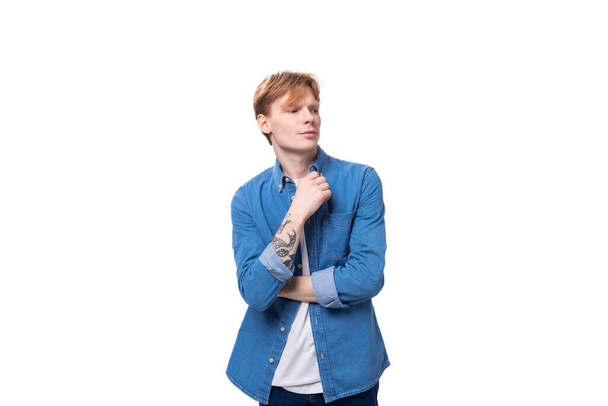 a young red-haired guy in a blue denim shirt actively gesticulates. advertising concept. - Photo, Image