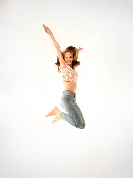 Cute young girl with jeans and pink top jumping energetically - Foto, Imagem