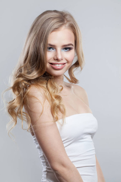 Joven y alegre mujer de la moda con cabello rubio saludable y maquillaje sobre fondo blanco - Foto, imagen