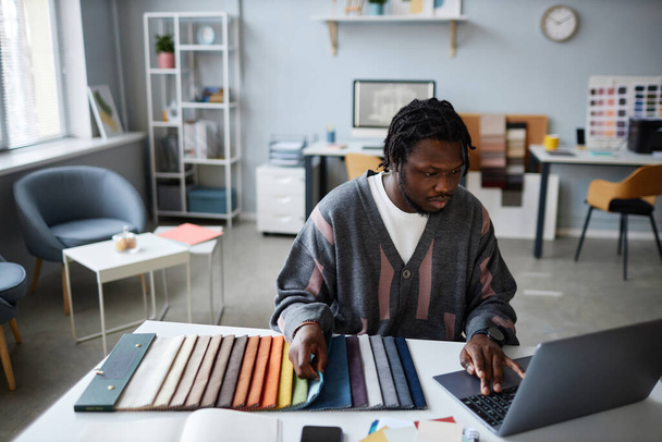 Designer afroamericano che lavora al suo posto di lavoro con il progetto, utilizza il computer per adattarsi al colore per gli interni - Foto, immagini
